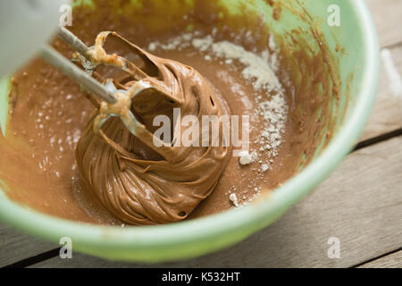 Overhead view of electric mixer mixing flour and chocolate batter in bowl on table Stock Photo