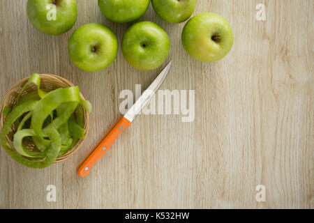 Overhead view of granny smith apples by peel in basket on table Stock Photo