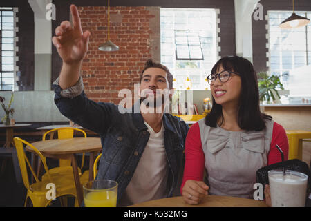 Man with young woman pointing while sitting in cafe Stock Photo