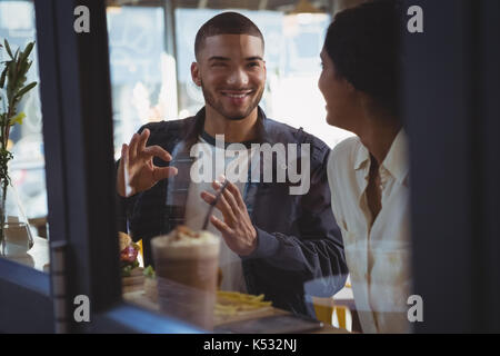 Smiling young couple looking each other seen through glass in cafe Stock Photo