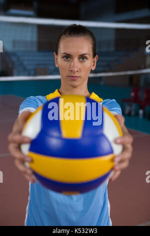 Portrait of young female sportsperson holding volleyball at court Stock Photo