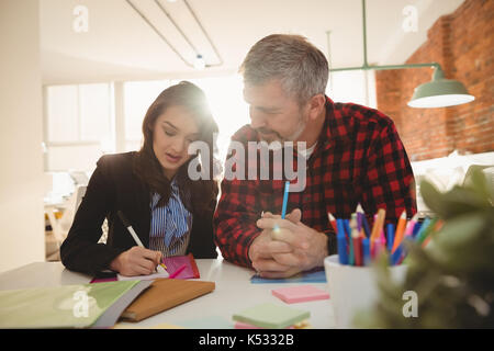 Business executives writing on sticky notes in office Stock Photo