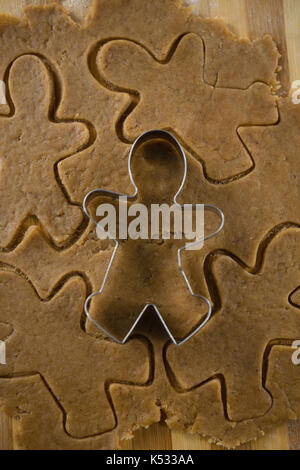 Gingerbread man pastry cutter on dough over cutting board Stock Photo