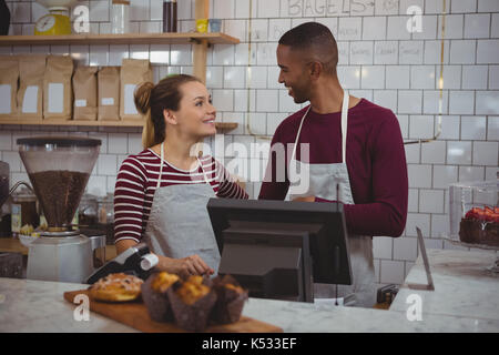 Young owners talking to each other while standing in cafe Stock Photo