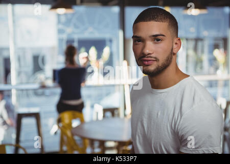 Portrait of young man with friend sitting in background at cafe Stock Photo