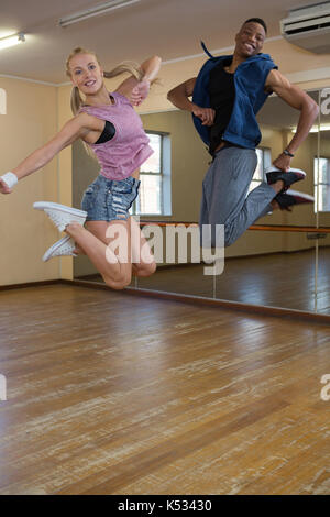 Full length portrait of dancers jumping at hardwood floor in studio Stock Photo