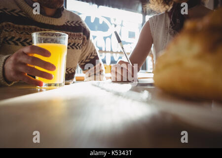 Midsection of young man with woman having juice at table in cafe Stock Photo