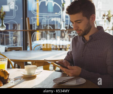 Young businessman using digital tablet while having breakfast in cafe Stock Photo