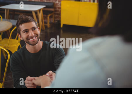 Smiling young man holding girlfriend hand at cafe Stock Photo