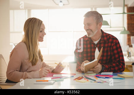 Smiling executives discussing over diary in office Stock Photo