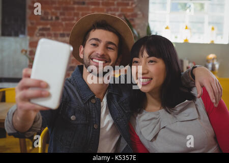 Happy young man with woman taking selfie at cafe Stock Photo