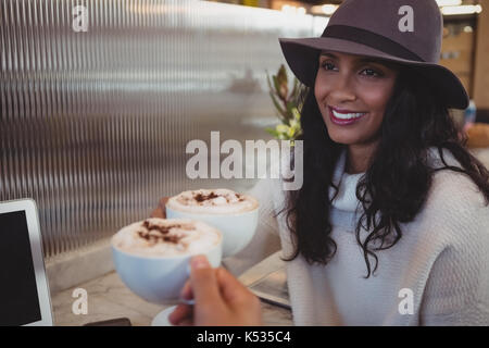 Cropped hand of man having coffee with smiling woman at counter in cafe Stock Photo
