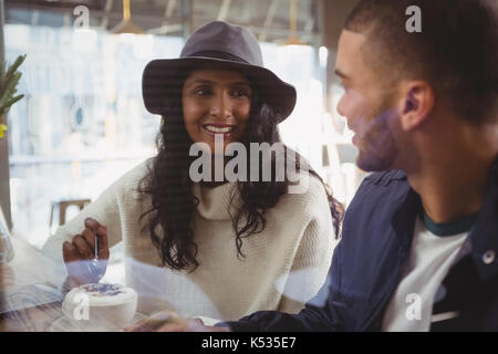 Smiling young couple having coffee seen through glass in cafe Stock Photo