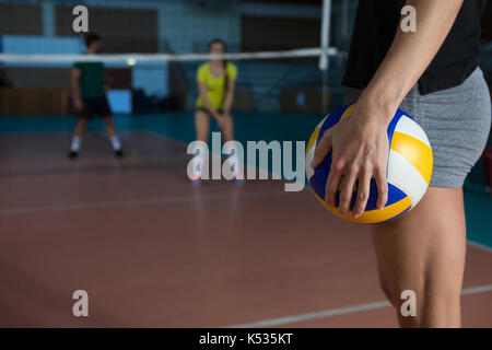 Mid section side view of female player holding volleyball at court Stock Photo