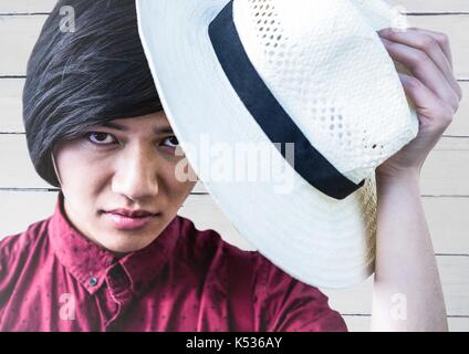 Digital composite of Close up of millennial man tipping hat against white wood panel Stock Photo