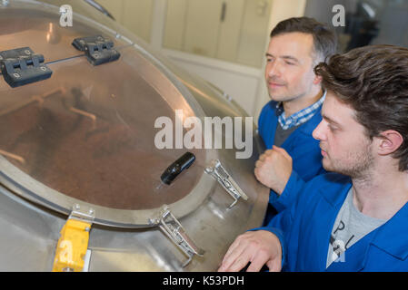 two workers at plant checking parameters of pressure Stock Photo
