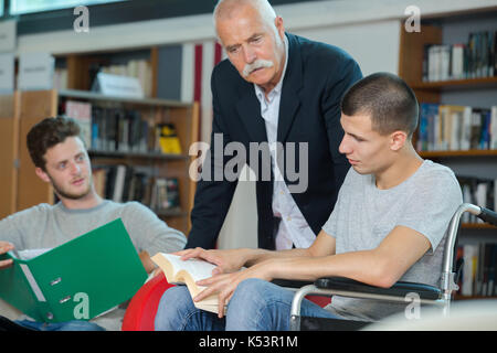 disabled student in the school library with friend and librarian Stock Photo