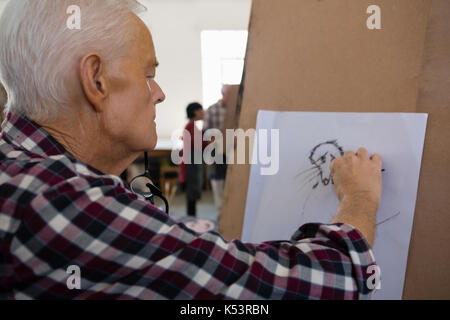 Close up of senior man sketching on paper in art class Stock Photo