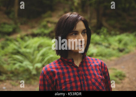 Thoughtful woman standing in forest Stock Photo