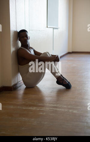 Depressed ballerino sitting against wall in the studio Stock Photo
