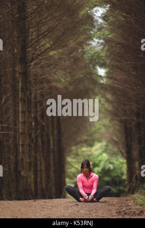 Woman performing stretching exercise in forest Stock Photo