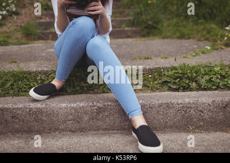 Woman sitting on stone steps in forest Stock Photo