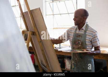 Senior man painting while standing in art class Stock Photo