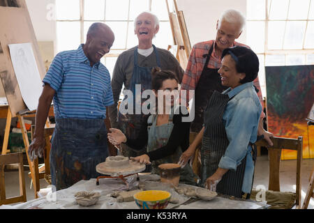 Happy friends with teacher at table in art class Stock Photo