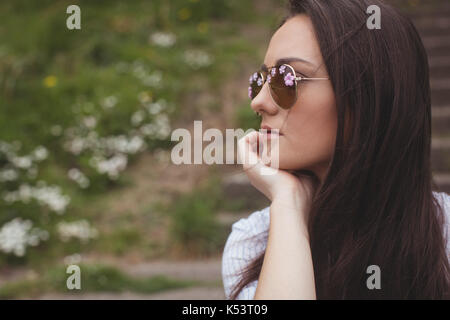 Thoughtful woman in sunglasses at forest Stock Photo