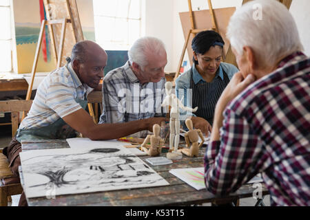 Friends discussing over painting while sitting at table in art class Stock Photo