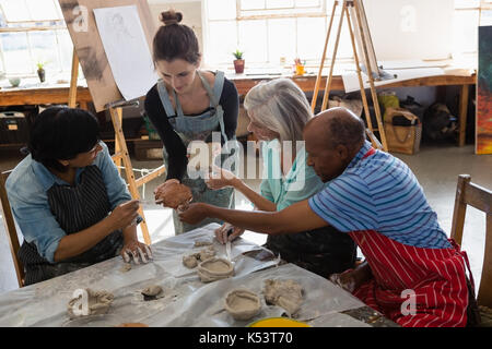 High angle view of female teacher showing clay to senior people at table in art class Stock Photo