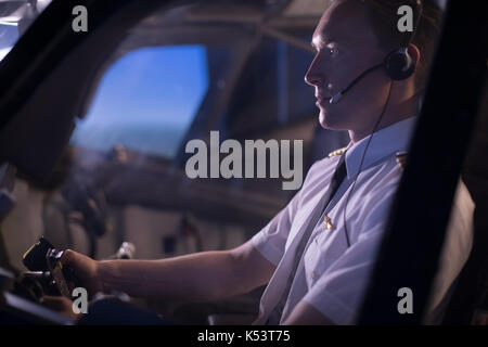 Side view of young male pilot flying airplane Stock Photo