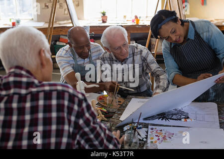 High angle view senior woman showing painting to male friends Stock Photo