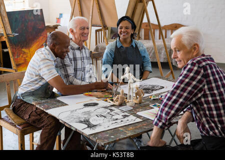 Happy senior friends talking at table in art class Stock Photo