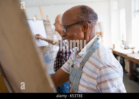 Side view of senior men painting on paper in art class Stock Photo