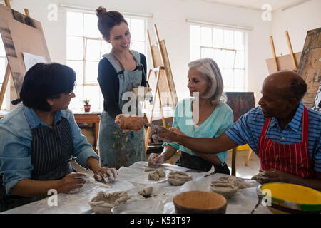 Female instructor showing clay to senior people at table in art class Stock Photo