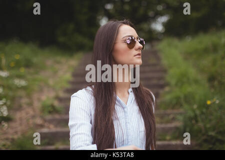Thoughtful woman in sunglasses at forest Stock Photo