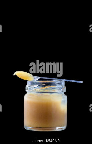 raw organic royal jelly in a small bottle with litte spoon on black Stock Photo