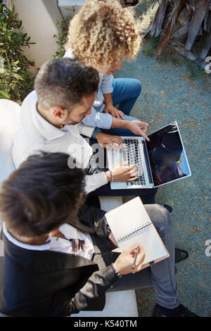 Aerial portrait of three men working together on laptop outside Stock Photo