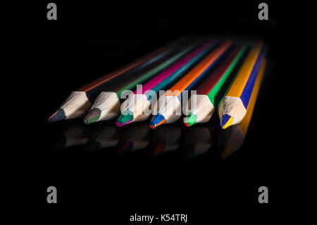Colored pencils on black background reflected in mirror. Pencils with double color on black isolated background. Stock Photo