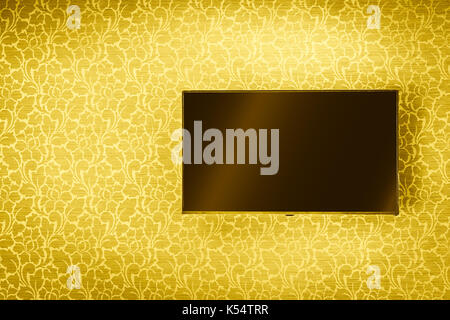 LCD TV Panel hanging on luxury golden wall background Stock Photo