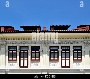 Traditional shop house exterior with brown wooden louvered shutters, ornate columns and carvings in the Joo Chiat District of Singapore Stock Photo
