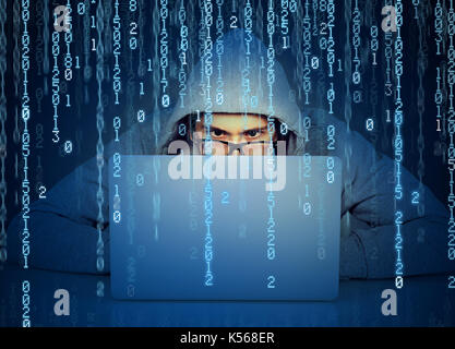 Young man hacker working on a laptop on binary code background Stock Photo