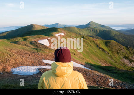 Alone tourist in yellow jacket on high mountains. Stock Photo