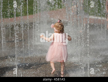 little girl plays with water in fountain Stock Photo