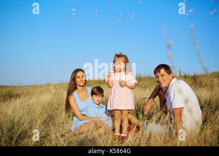 Happy family blowing soap bubbles in park Stock Photo - Alamy
