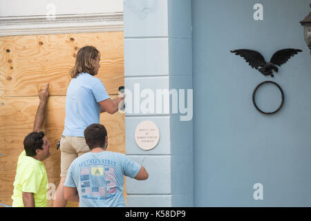 Workers secure plywood covering on a historic building on Broad Street in preparation for Hurricane Irma September 8, 2017 in Charleston, South Carolina. Imra is expected to spare the Charleston area but hurricane preparations continue as Irma leaves a path of destruction across the Caribbean. Stock Photo