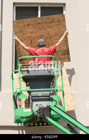 A worker use plywood to cover windows on historic Broad Street in preparation for Hurricane Irma September 8, 2017 in Charleston, South Carolina. Imra is expected to spare the Charleston area but hurricane preparations continue as Irma leaves a path of destruction across the Caribbean. Stock Photo