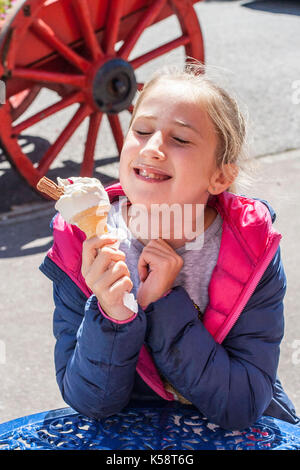Girl eating ice cream cone with a chocolate flake in it on a warm summer day, best life concept, happiness is, joy concept, bliss, 99, sunny day Stock Photo
