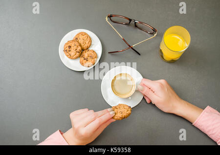 Woman hand having breakfast, coffee, orange juice, cookies. Stock Photo
